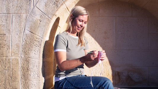 Woman happily crocheting outside